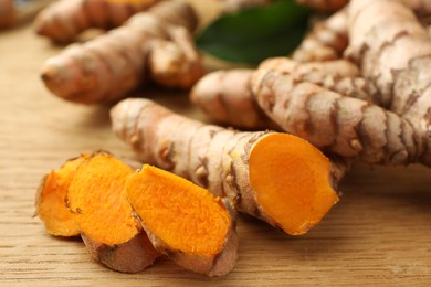 Photo of Cut turmeric roots on wooden table, closeup