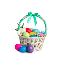 Wicker basket with bright painted Easter eggs and spring flowers on white background