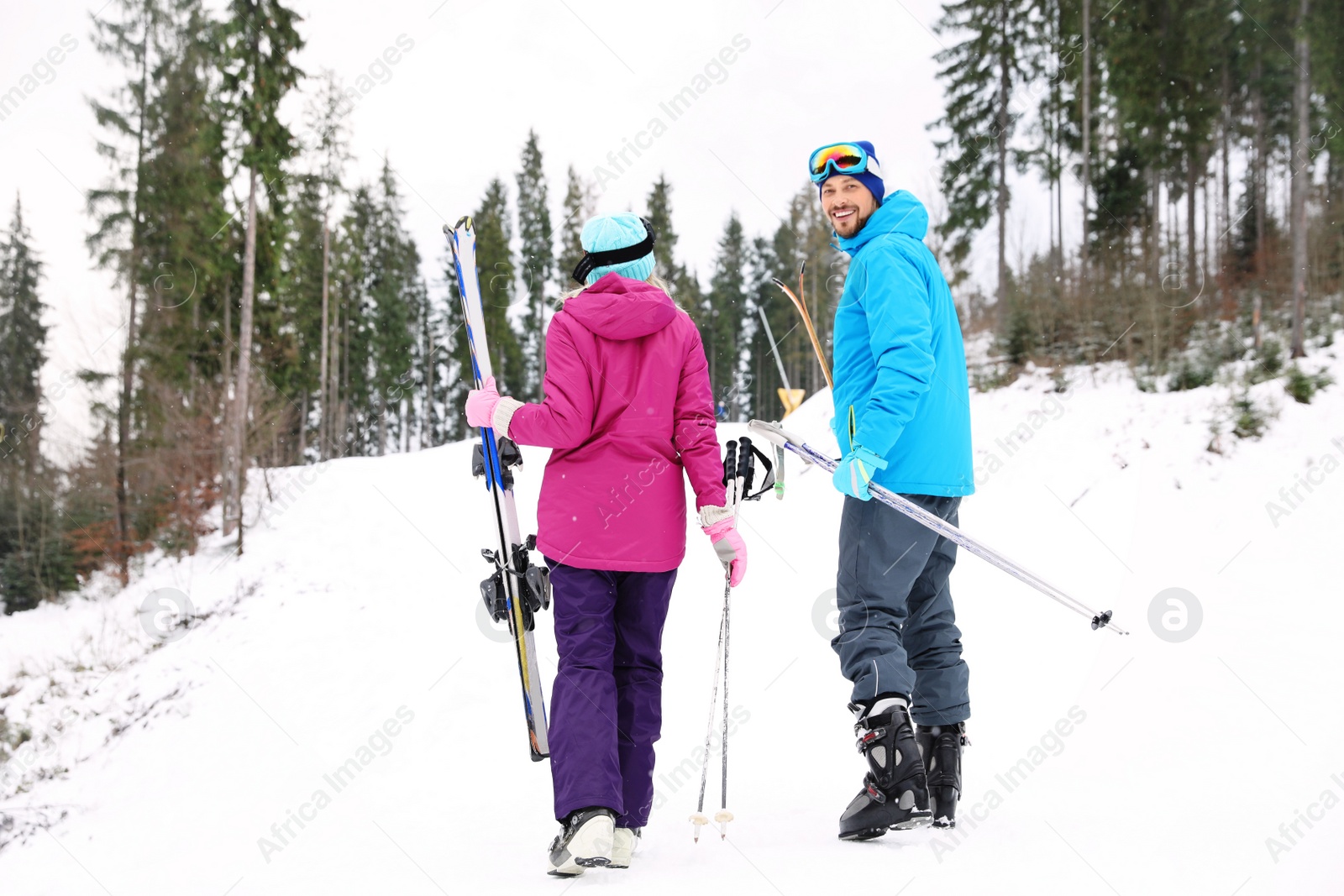 Photo of Couple of skiers on slope at resort. Winter vacation