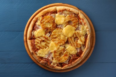 Delicious pineapple pizza on blue wooden table, top view