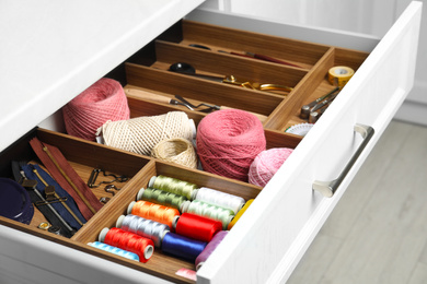Photo of Sewing accessories in open desk drawer indoors