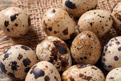 Photo of Fresh quail eggs on burlap fabric, closeup