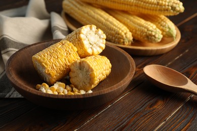 Tasty sweet corn cobs on wooden table