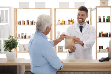 Pharmacist giving medicine to customer in drugstore