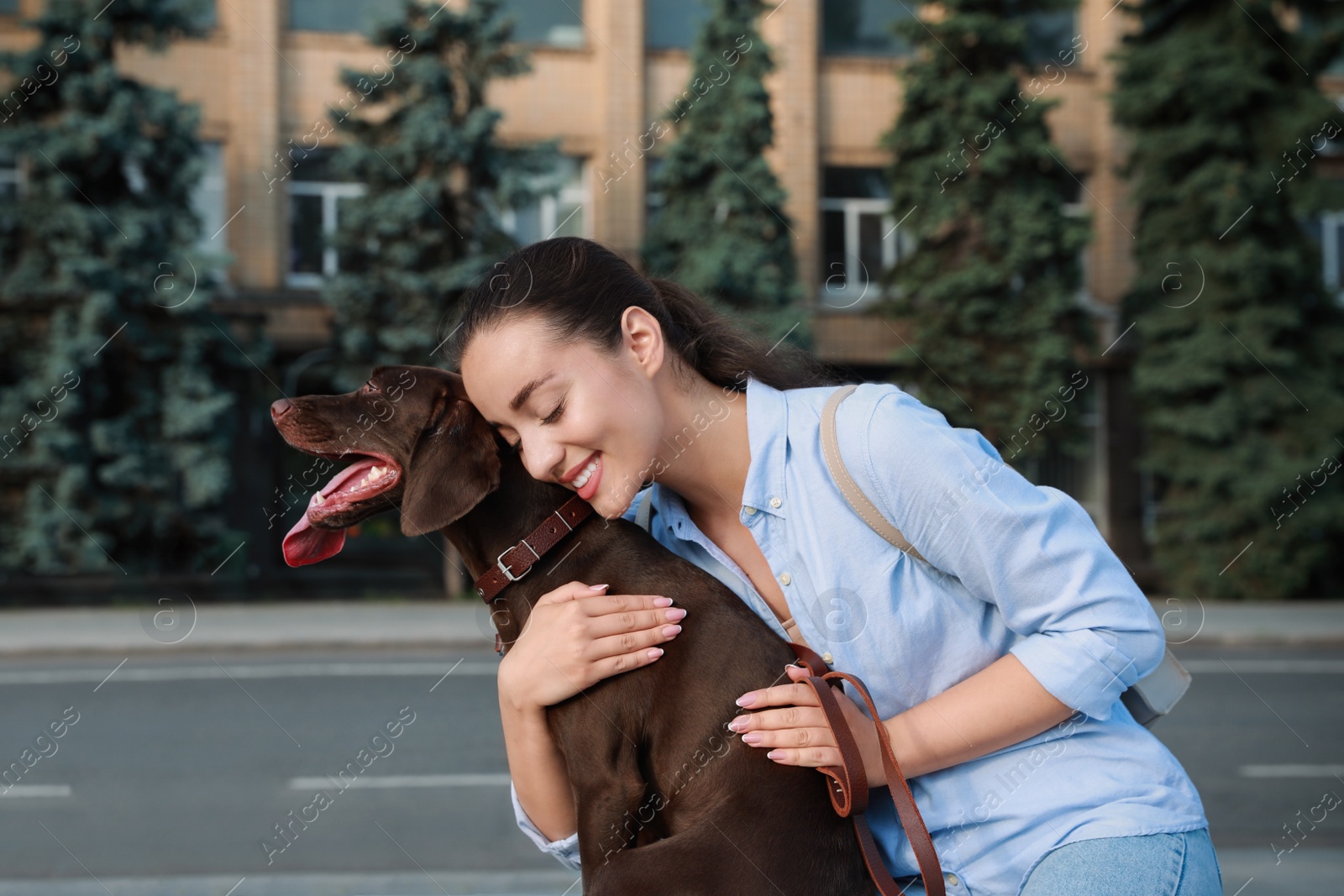 Photo of Happy woman hugging her German Shorthaired Pointer dog on city street