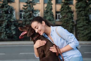 Photo of Happy woman hugging her German Shorthaired Pointer dog on city street