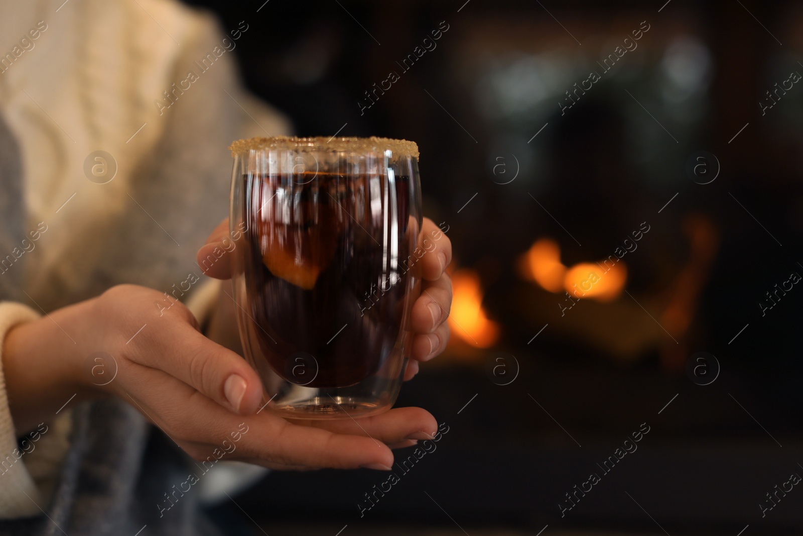 Photo of Woman with tasty mulled wine near fireplace indoors, closeup