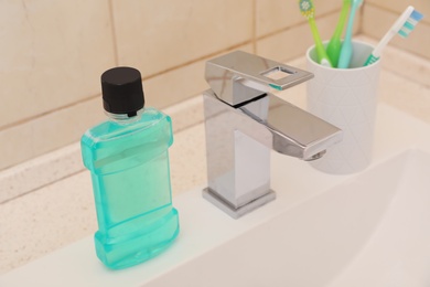 Mouthwash and holder with toothbrushes on sink in bathroom. Teeth and oral care