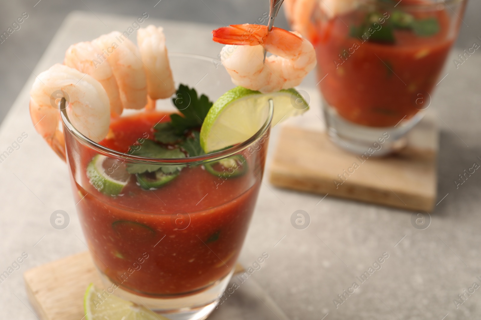 Photo of Tasty shrimp cocktail with sauce in glasses and lime on light grey table, closeup