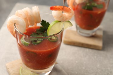 Tasty shrimp cocktail with sauce in glasses and lime on light grey table, closeup