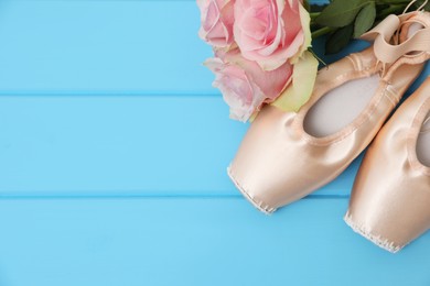 Photo of Beautiful beige ballet shoes and rose flowers on light blue wooden table, flat lay. Space for text