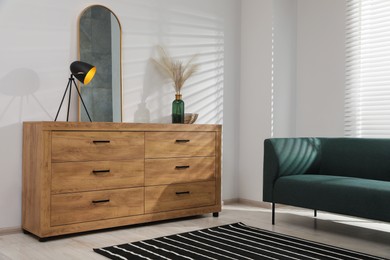 Photo of New wooden chest of drawers near sofa in stylish room