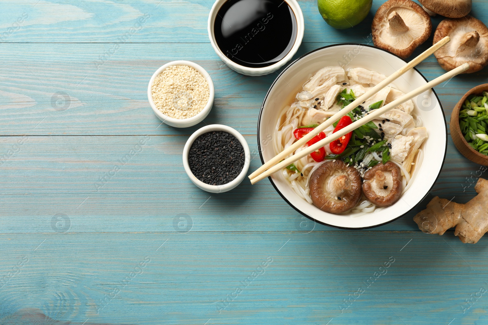 Photo of Delicious ramen with meat and ingredients on light blue wooden table, flat lay. Space for text