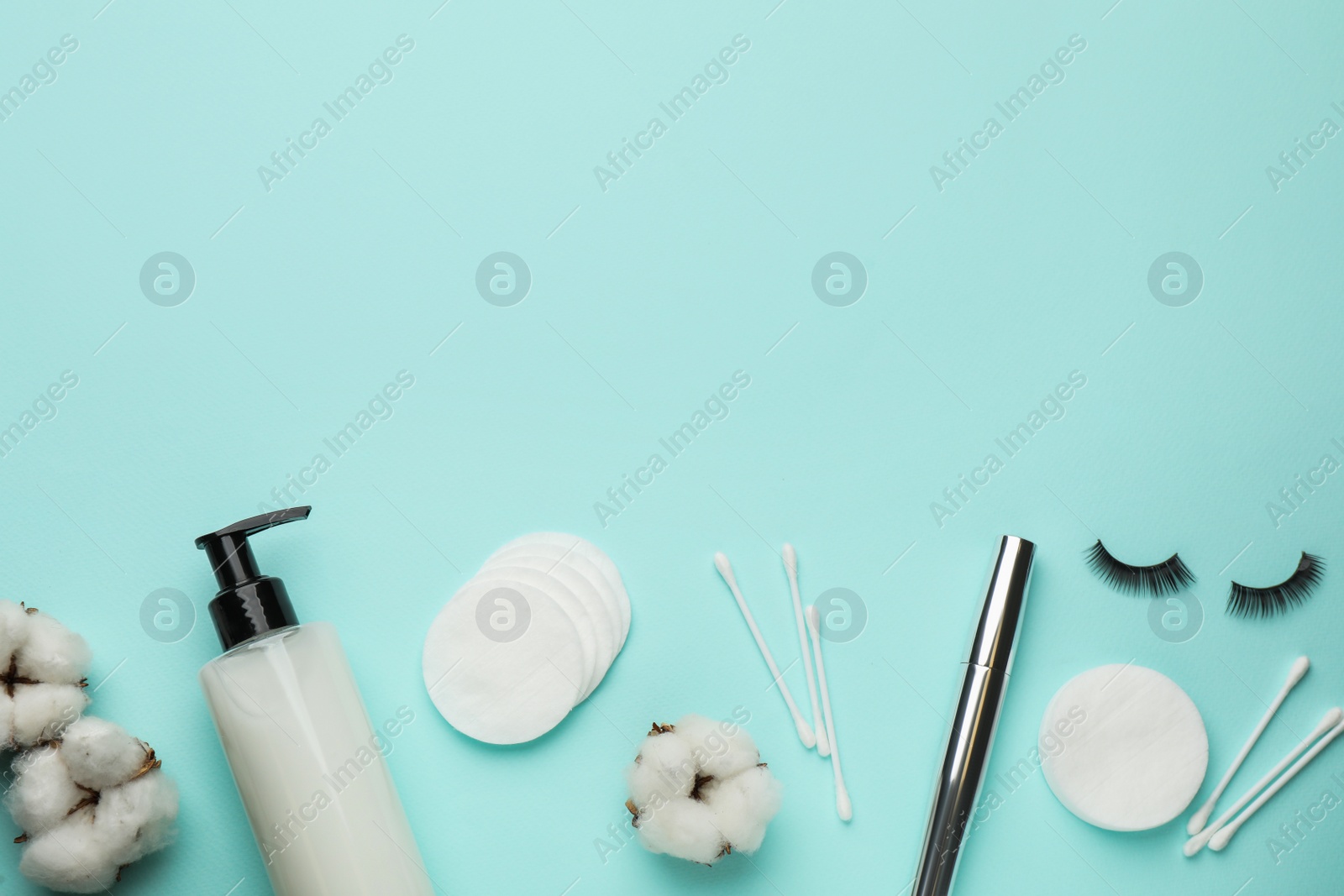 Photo of Cotton pads, swabs, mascara and makeup removal product on light blue background, flat lay. Space for text