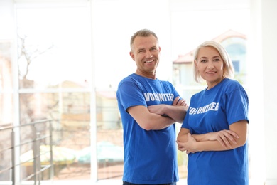 Photo of Portrait of happy volunteers in uniform indoors. Space for text