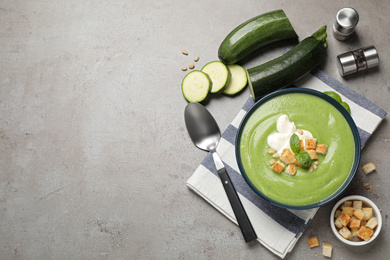 Photo of Tasty homemade zucchini cream soup on grey table, flat lay. Space for text