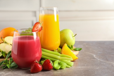 Photo of Glasses with different juices and fresh fruits on table against blurred background. Space for text