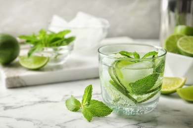 Refreshing beverage with mint and lime in glass on table