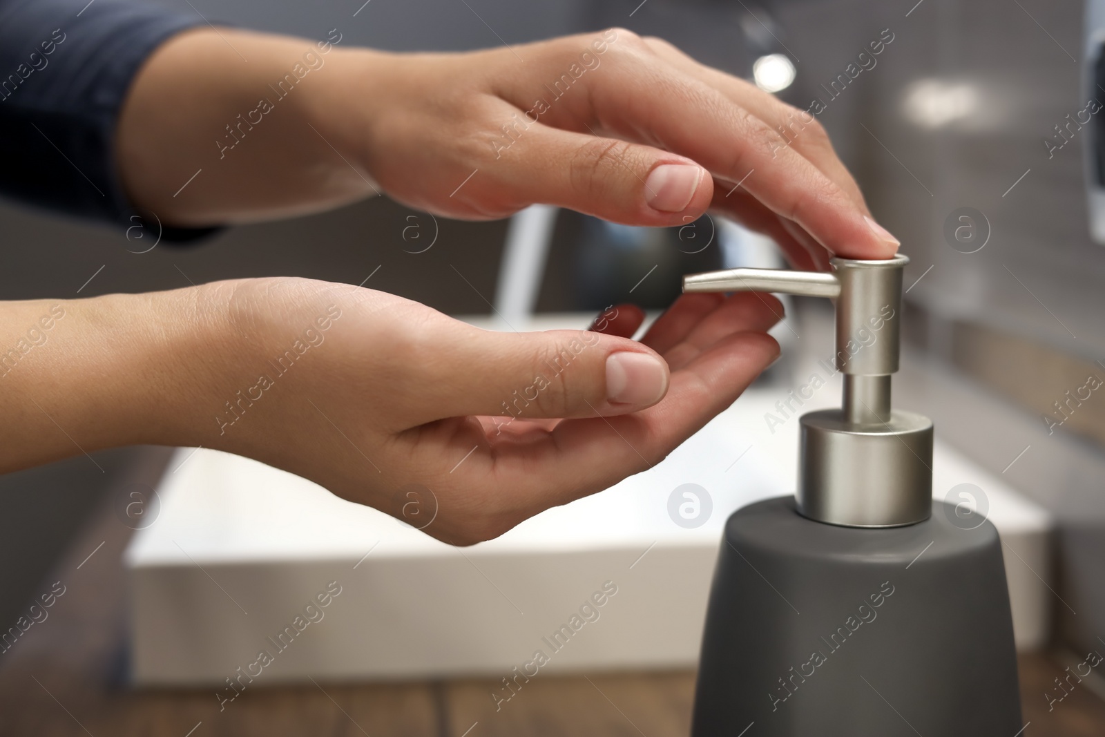 Photo of Woman using liquid soap dispenser in bathroom, closeup