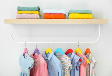Rack with different clothes on light background