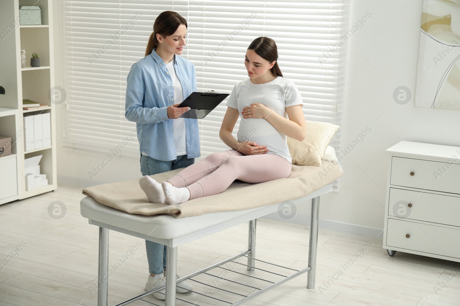 Photo of Doula working with pregnant woman indoors. Preparation for child birth