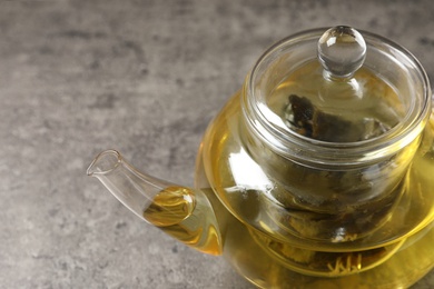 Photo of Glass teapot with oolong on grey table, closeup. Space for text