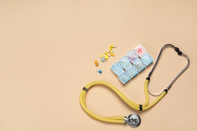 Photo of Stethoscope and pills on beige background, flat lay. Space for text