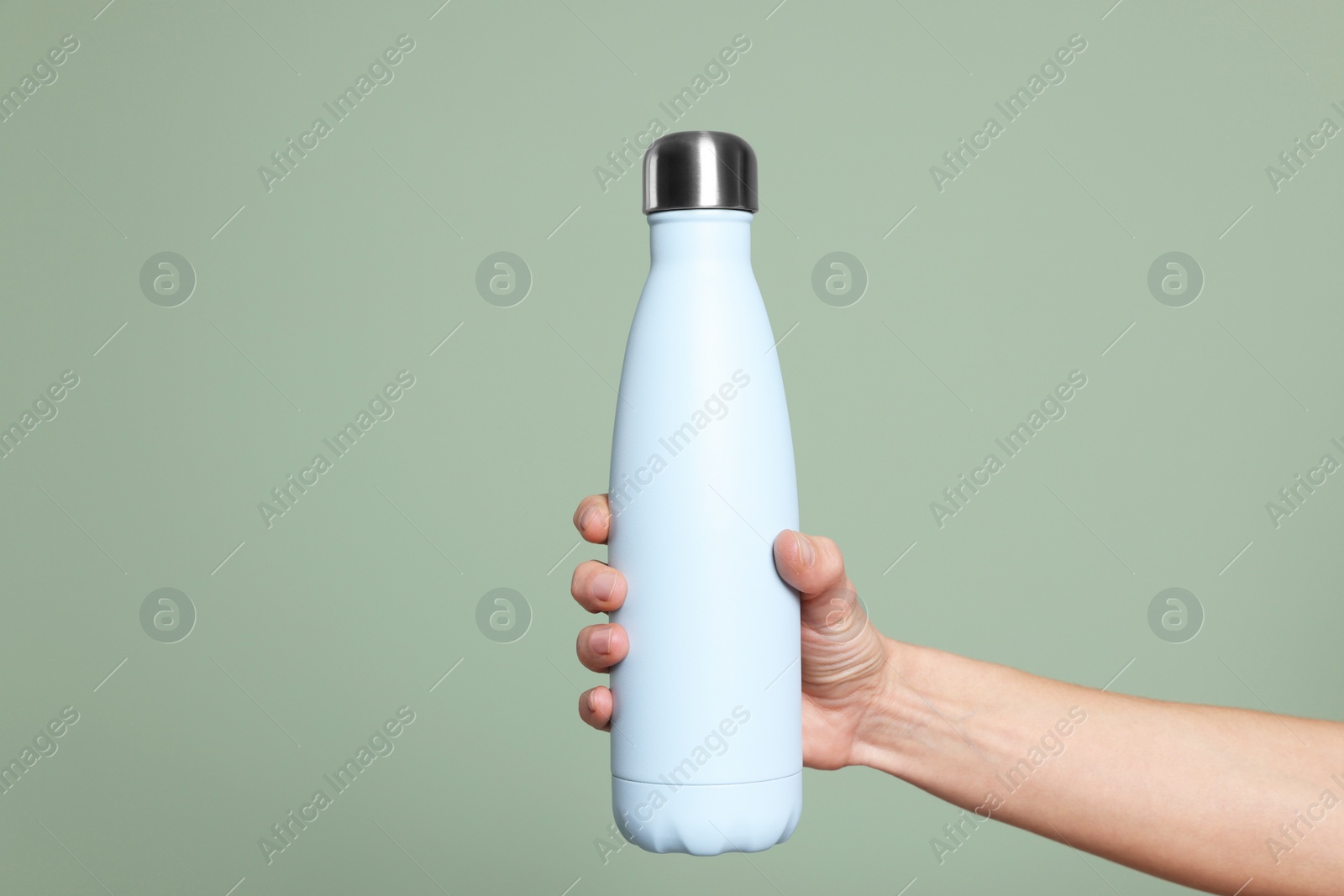 Photo of Woman holding thermo bottle on green background, closeup