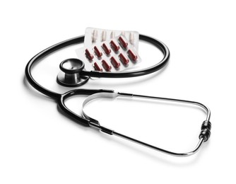 Stethoscope and different pills on white background