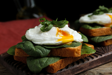 Photo of Delicious poached egg sandwich served on wooden board