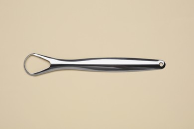 Photo of Metal tongue cleaner on beige background, top view