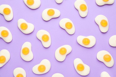 Photo of Tasty jelly candies in shape of egg on lilac background, flat lay