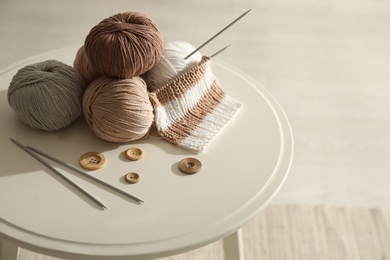 Yarn balls, buttons and knitting needles on white table indoors. Creative hobby