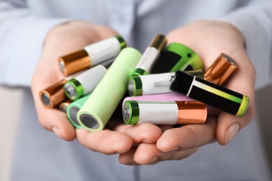 Image of Woman holding many used electric batteries in her hands, closeup