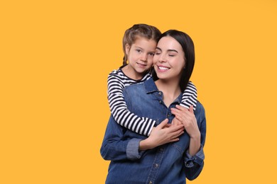 Photo of Happy woman with her cute daughter on yellow background. Mother's day celebration