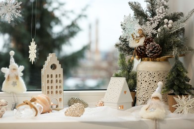 Many beautiful Christmas decorations and fir branches on window sill indoors