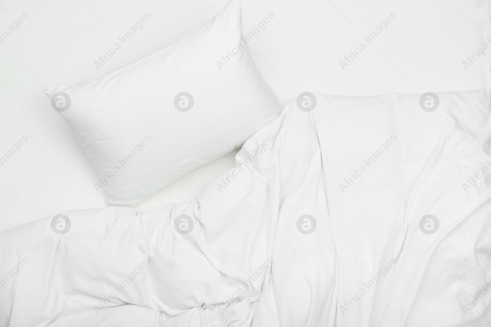 Photo of Soft white pillow and blanket on bed, top view