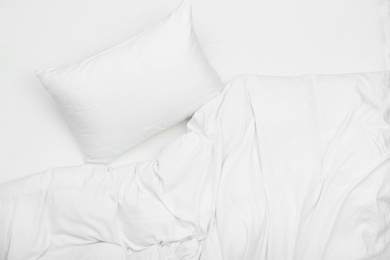 Soft white pillow and blanket on bed, top view