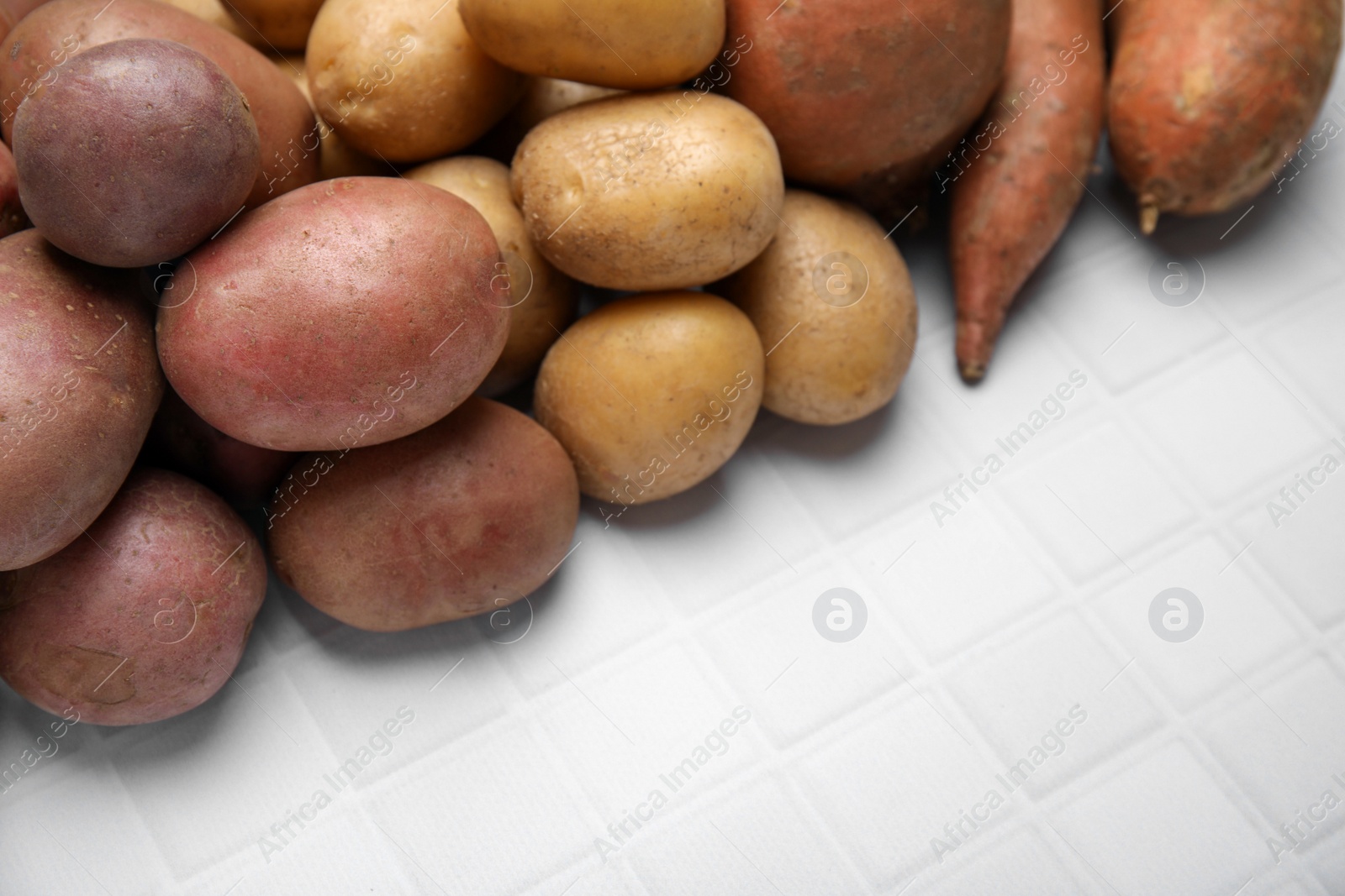 Photo of Different types of fresh potatoes on white table, closeup