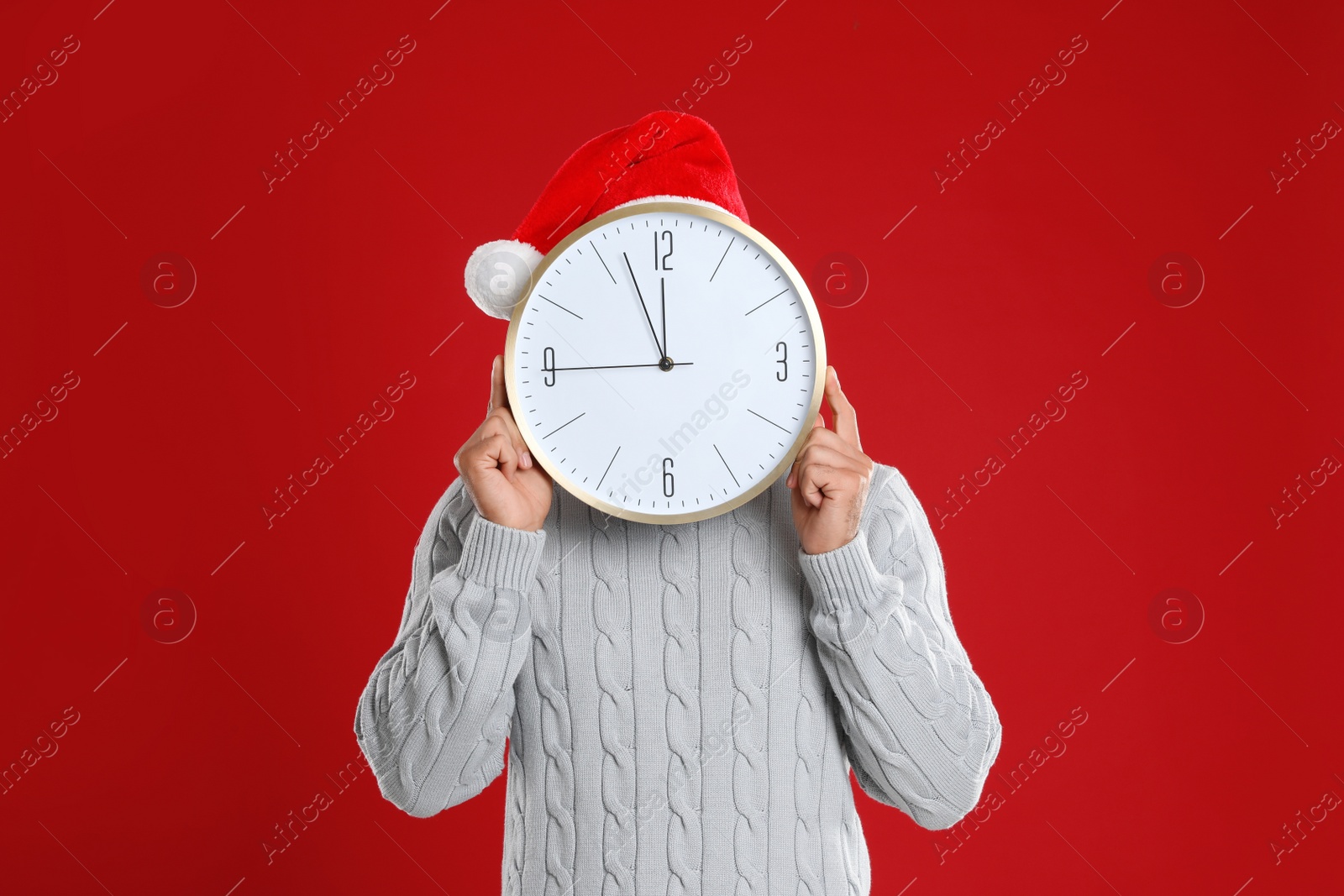 Photo of Man in Santa hat with clock on red background. New Year countdown