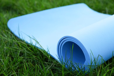 Blue karemat or fitness mat in fresh green grass outdoors, closeup