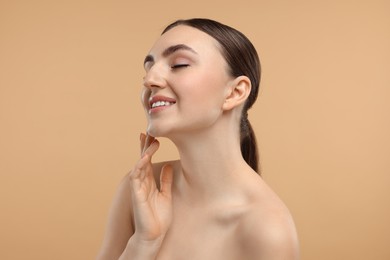Photo of Smiling woman touching her chin on beige background