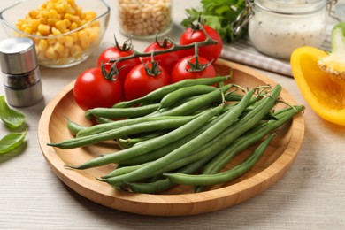 Photo of Fresh green beans and other ingredients for salad on white wooden table