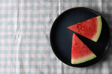 Photo of Sliced fresh juicy watermelon on checkered light blue tablecloth, top view. Space for text