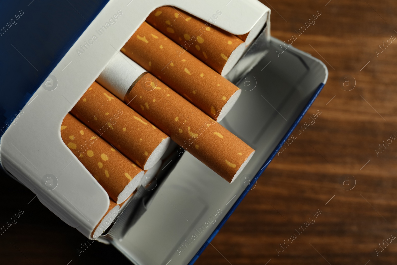 Photo of Pack of cigarettes on wooden table, closeup