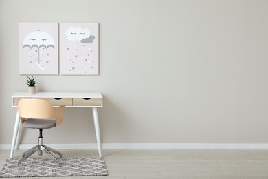 Photo of Children's room interior with desk, cute paintings and empty wall. Space for design