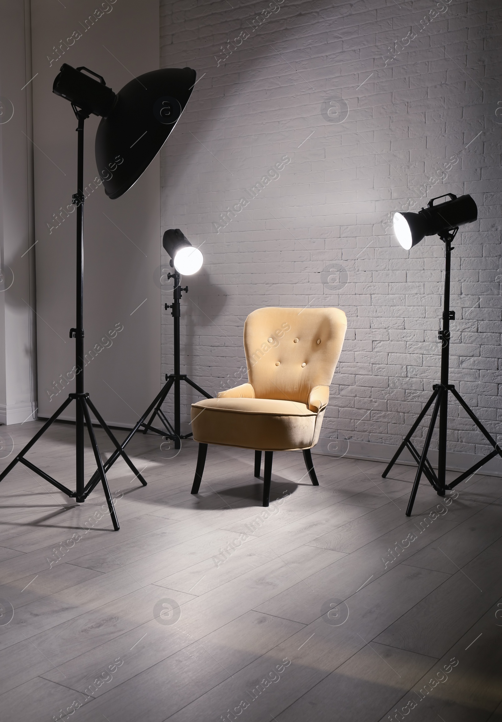 Photo of Interior of modern photo studio with professional lighting equipment and armchair