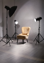 Interior of modern photo studio with professional lighting equipment and armchair