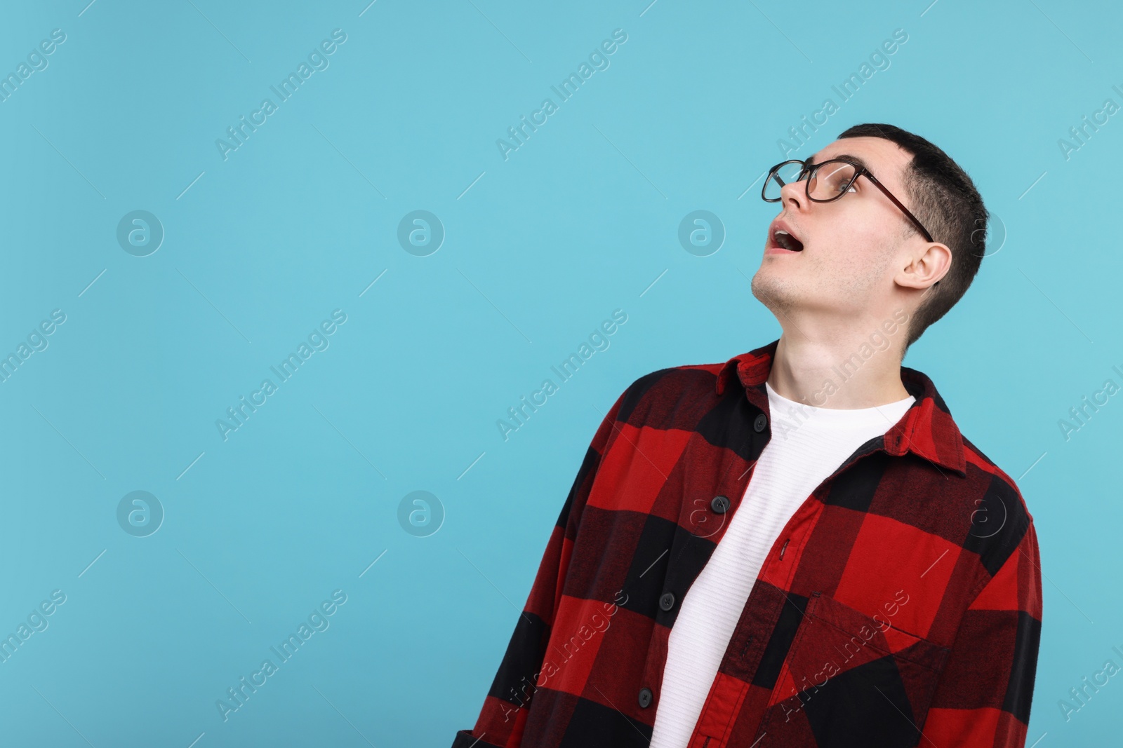 Photo of Surprised man in glasses on light blue background, space for text