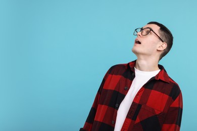 Surprised man in glasses on light blue background, space for text